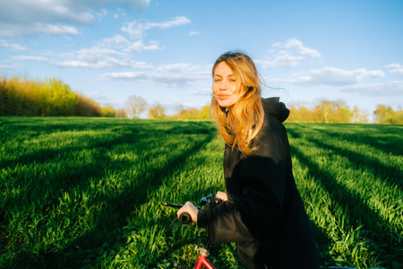 Portrait of young caucasian attractive woman with bicycle at the field in countryside .の写真素材