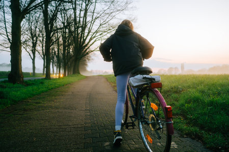 Woman cyclist riding on bicycle in the park in springtime.の写真素材