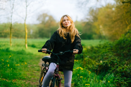 Portrait of young attractive woman riding on bicycle in the park in springtime.の写真素材