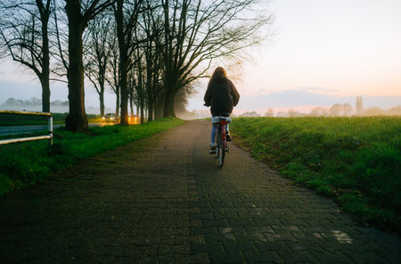 Woman cyclist riding on bicycle in the park in springtime.の写真素材