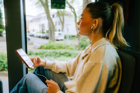 An attractive caucasian woman using a smartphone in a city bus. Young beautiful woman using public transportation.の写真素材