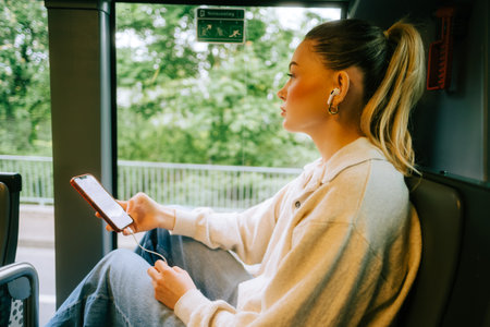 An attractive caucasian woman using a smartphone in a city bus. Young beautiful woman using public transportation.の写真素材