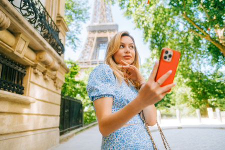 Young attractive woman making selfie photo using mobile phone near Eiffel Tower in Paris France, Woman tourist traveling on Europeの写真素材