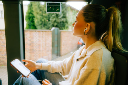 An attractive caucasian woman using a smartphone in a city bus. Young beautiful woman using public transportation.の写真素材