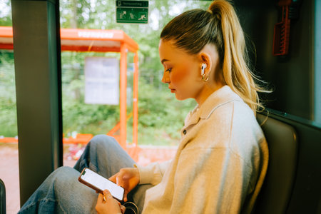 An attractive caucasian woman using a smartphone in a city bus. Young beautiful woman using public transportation.の写真素材