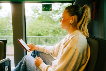 An attractive caucasian woman using a smartphone in a city bus. Young beautiful woman using public transportation.の写真素材