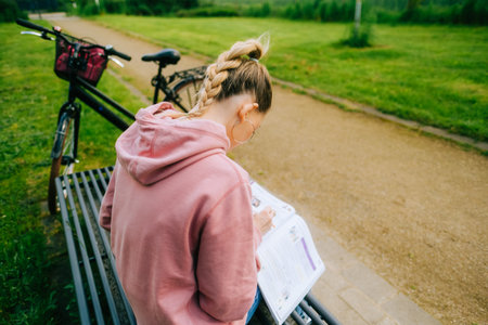 Young attractive caucasian woman student making home work outdoors on a bench in a park.の写真素材