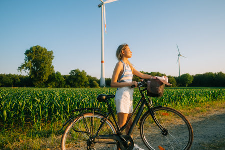 Portrait of young attractive woman with bike at the countryside field in sunset.の写真素材