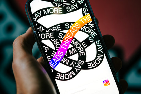 Threads app logo on iPhone screen in hands.