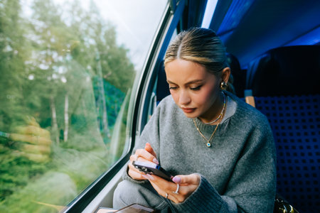 Attractive caucasian woman using a smartphone in regional train. Young beautiful woman using public...