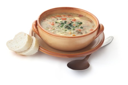Creamy vegetable soup with two slices of bread isolated on white.の写真素材