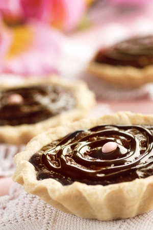 Delicious chocolate tarts with chocolate frosting and pink background.の写真素材