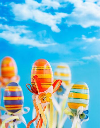 Colorful easter eggs with ribbons on blue sky backgroundの写真素材