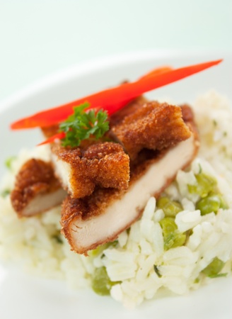 Chicken fried with eggs and bread crumbles and served with peas risottoの写真素材