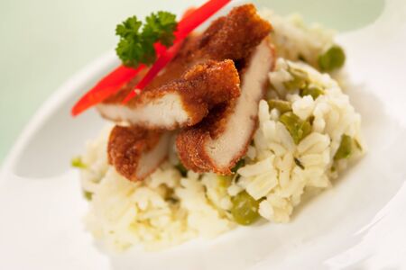 Chicken fried with eggs and bread crumbles and served with peas risottoの写真素材