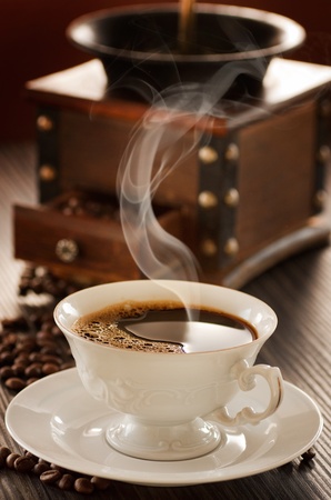 Cup of coffee in front of vintage coffee grinder.の写真素材