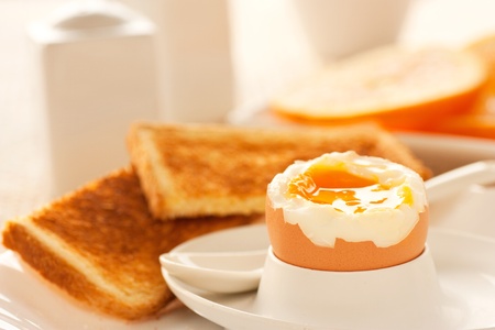 Soft boiled egg with toasted bread and slices of oranges in the back. Shallow depth of filed.の写真素材