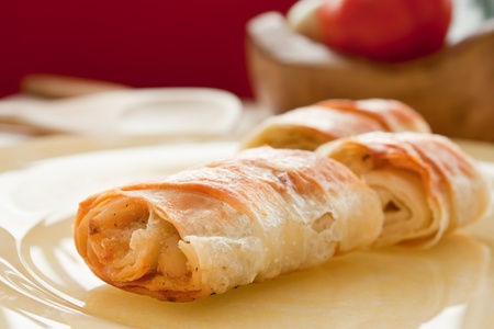 Potato filo pastry with vegetables and cutlery in the back.