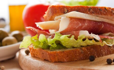 Prosciutto and cheese sandwich with olives and lettuce.の写真素材