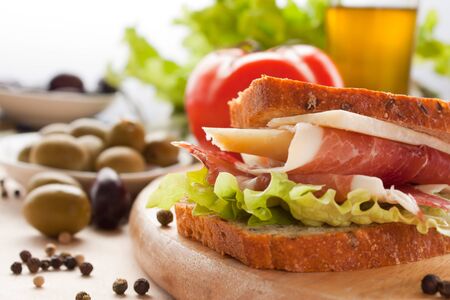Prosciutto and cheese sandwich with olives and lettuce.の写真素材