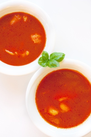 Delicious tomato soup with basil leaves and home made egg noodles. Shallow depth of field.の写真素材