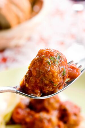Close up of meat ball on a fork in front of the plate .の写真素材
