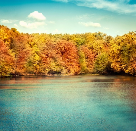 Nature landscape with beautiful lake in autumn with colorful trees and blue sky with cloudscape in the background.の写真素材