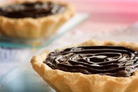 Delicious chocolate tarts with chocolate frosting and pink background.の写真素材