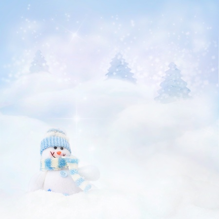 Christmas blue background. Snowman toy on the bokeh winter background in the snow and magical forest with Christmas shiny trees.の写真素材