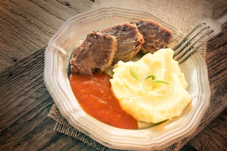 Healthy eating. Boiled beef with mashed potates and tomato sauce in rustic wooden settingの写真素材