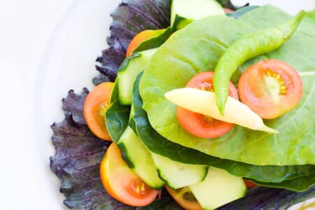 Vegetable healthy salad arranged in pyramid with copyspace. Cherry tomatoes, spinach, lettuce, cucumber, cabbage and chilli pepper.の写真素材
