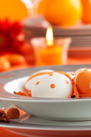 Easter table setting in orange tones with candles and flower.の写真素材