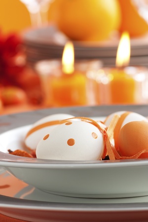 Easter table setting in orange tones with candles and flower.の写真素材