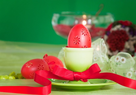 Easter table setting in green and red tones with candles and bouquet.の写真素材