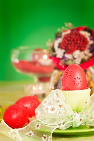 Easter table setting in green and red tones with candles and bouquet.の写真素材