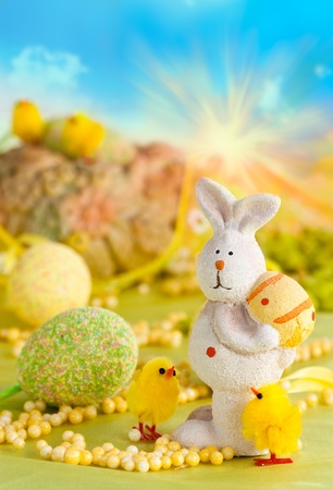 Easter setting with Easter eggs, chicks and rabbit and blue sky in the back.の写真素材