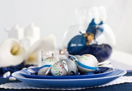 Easter table setting in blue and white tones with candles and flower.の写真素材