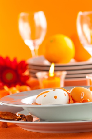 Easter table setting in orange tones with candles and flower.の写真素材