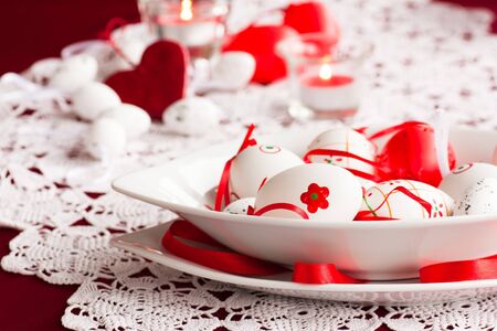 Easter table setting in red tones with candles and flower.の写真素材