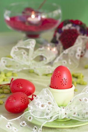 Easter table setting in green and red tones with candles and bouquet.の写真素材