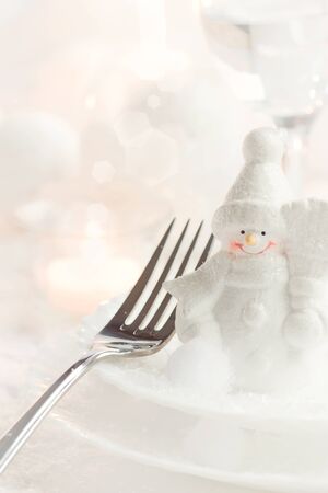 Christmas table setting. Fork and knife in elegant holiday setting with snow and white ornamentsの写真素材