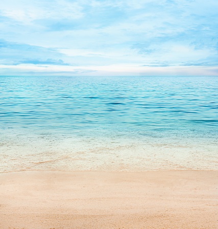 Summer or spring abstract background. Golden sand with blue ocean and cloudscape and sunset in the back.の写真素材