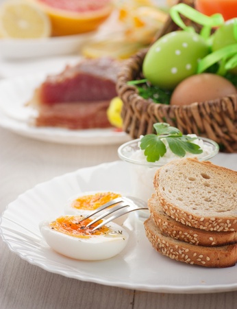 Traditional Easter breakfast. Table setting with Boiled eggs with ham, cottage cheese and Easter decorationsの写真素材
