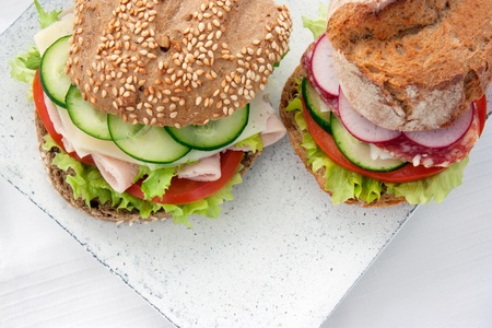 Delicious ham, cheese and salami sandwich with vegetables, lettuce, cherry tomatoesの写真素材