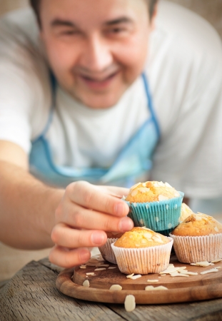 Happy baking. Chef is decorating delicious organic muffins. Almond and cherry cup cakes in natural setting.の写真素材