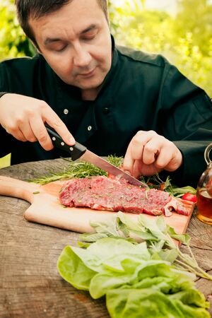 Cooking ingredients: marinated meat,oil,vinegar, herbs and vegetables. Chef is carving and marinating meat.の写真素材