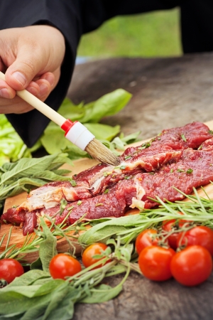 Cooking ingredients: marinated meat,oil,vinegar, herbs and vegetables. Chef is carving and marinating meat.の写真素材