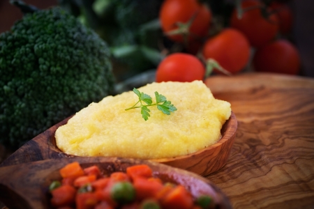 Vegetarian dinner. Corn meal or polenta with peas and carrots in sauce. Broccoli and tomato in the backgroundの写真素材