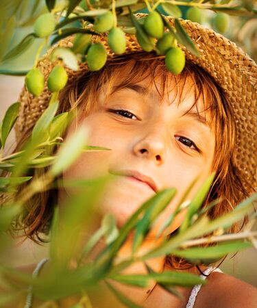 Beautiful little girl in summer olive tree garden. Child nature concept background. Olive harvestの写真素材