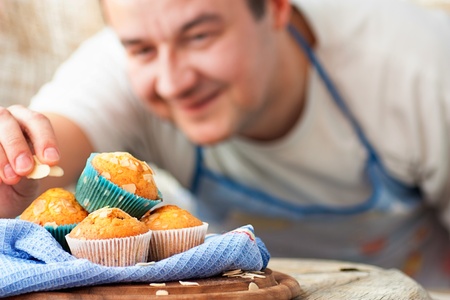 Chef is decorating delicious organic muffins. Almond and cherry cup cakes in natural setting.